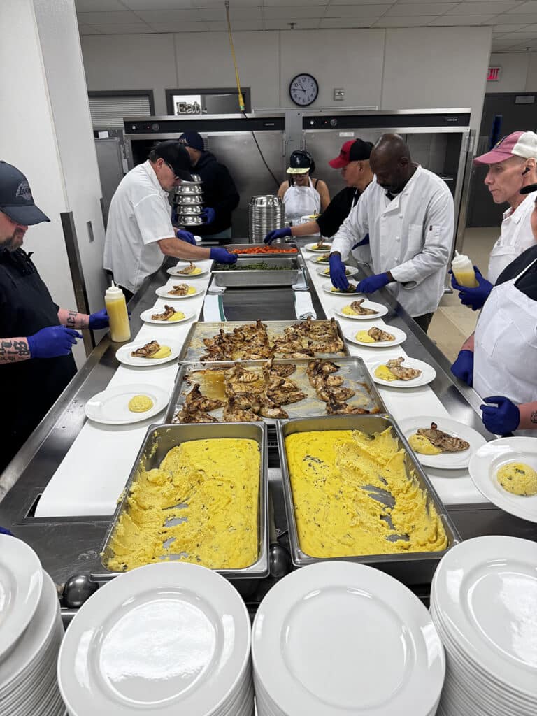crew platting dishes on a mass feed conveyor belt system